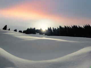 Dawn in the winter mountains of Central Asia. The morning sun peeks out from behind the mountain,...