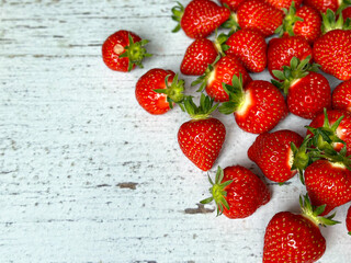 A horizontal close-up shot of ripe, juicy, fresh strawberries. Red strawberries on a light wooden table, top view. 