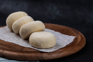 Frozen syrniki (cottage cheese pancakes) with vanilla flavor on dark black background, semi-finished, ready for cooking. Convenience and homemade frozen healthy meals.