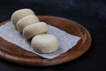 Frozen syrniki (cottage cheese pancakes) with vanilla flavor on dark black background, semi-finished, ready for cooking. Convenience and homemade frozen healthy meals.