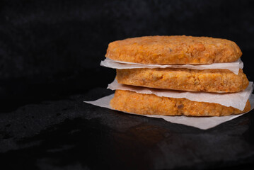 Frozen fish cutlets on dark black background, semi-finished, ready for cooking. Convenience and homemade frozen healthy meals.