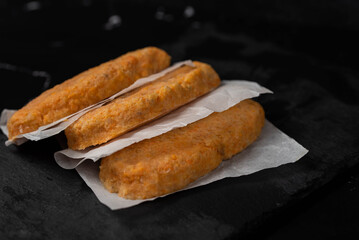 Frozen fish cutlets on dark black background, semi-finished, ready for cooking. Convenience and homemade frozen healthy meals.