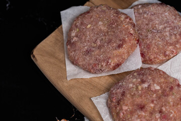 Frozen meat cutlets on dark black background, semi-finished, ready for cooking. Convenience and homemade frozen healthy meals.