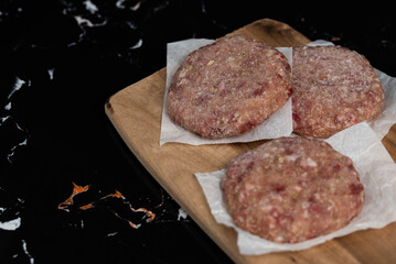 Frozen meat cutlets on dark black background, semi-finished, ready for cooking. Convenience and homemade frozen healthy meals.