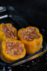 Frozen stuffed peppers filled with meat and rice, on dark black background, semi-finished, ready for cooking. Convenience and homemade frozen healthy meals.