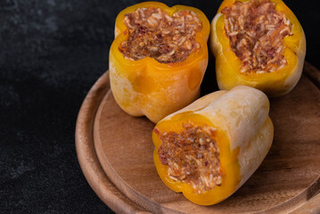 Frozen stuffed peppers filled with meat and rice, on dark black background, semi-finished, ready for cooking. Convenience and homemade frozen healthy meals.