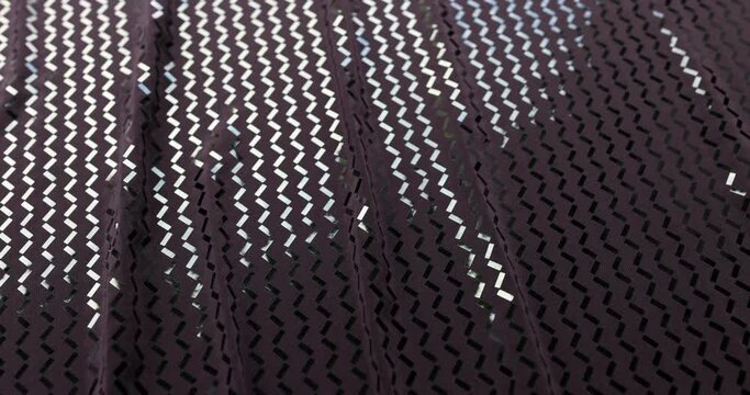 Closeup of dark purple fabric with geometric pattern of small light purple interlocking diamonds