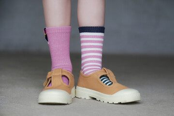 Kid wears different pair of socks. Child foots in mismatched socks standing outdoor.  Down syndrome...