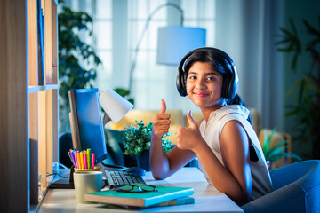 Indian asian teenage girl student using headphone and computer for studying at home