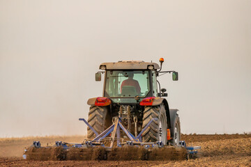 A tractor with plow in action, turning over the soil on a sunny day