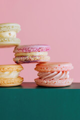Stacked colorful macarons against a pink and green background