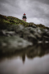 Red and white striped Quoddy lighthouse reflected in tide pool, Maine