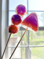 Candied strawberries and grapes on skewers by kitchen window