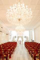 Luxurious wedding ceremony with red and gold chairs and floral arch