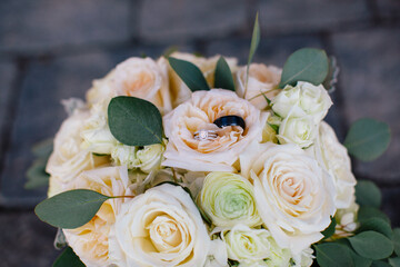 Wedding rings nestled in a bouquet of white roses and greenery