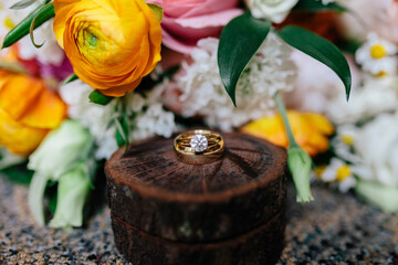 Wedding rings on rustic wood amid vibrant floral bouquet