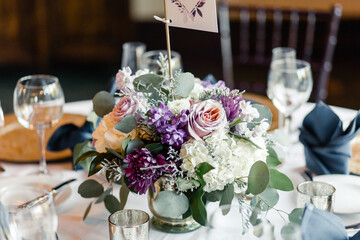 Table centerpiece with purple, white flowers, and glassware