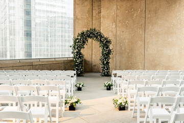 Wedding ceremony setup with rows of white chairs and a floral arch.
