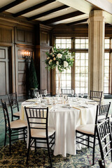 Indoor table setting with tall floral centerpiece and black chairs