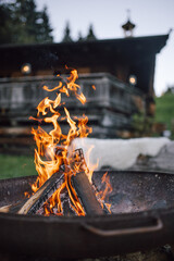 Crackling campfire with wooden cabin in the background