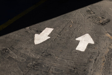 Two white directional arrows on a concrete floor