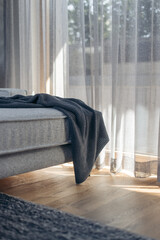 Sunlit sofa with blanket and curtains