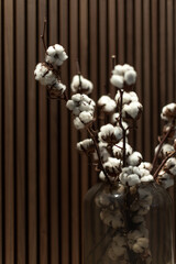 Cotton branches in a glass vase against a wooden background