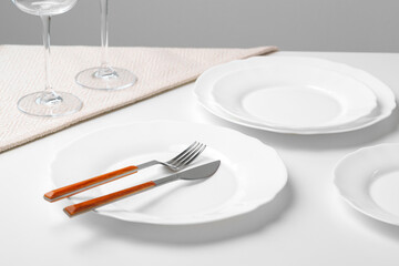 Stylish table setting with white dishware on white tablecloth