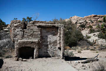 Ruined stone structure in desert landscape with rocky backdrop
