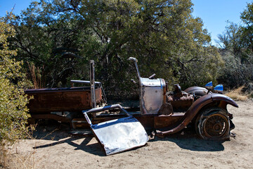 Abandoned vintage car wreck in a desert woodland