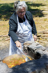 woman cook with white apron cooking a typical Spanish paella