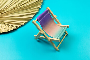 Colorful beach chair, dried palm leaf on blue background. Summer, holidays and beach concept....