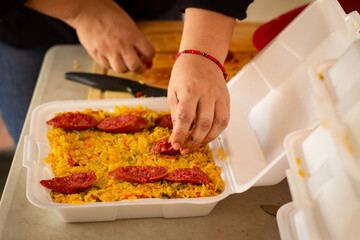 Latin woman prepares chorizo ​​for a paella in her small business