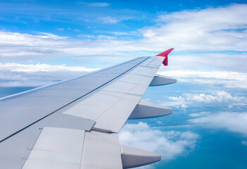 Fototapeta premium Clear blue sky with fluffy ornamental cumulus clouds, panoramic view from an airplane, wing close-up.