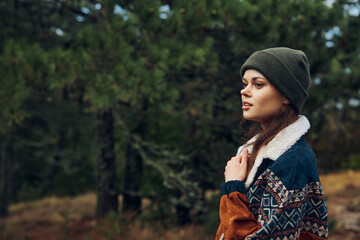 Beautiful young woman in a stylish sweater and hat, enjoying nature in a serene forest setting Portrait of fashion and beauty in the woods