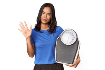 Filipino woman with scale in studio smiling cheerful showing number five with fingers.