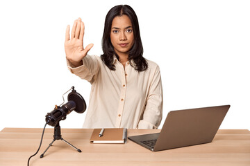 Woman records podcast with laptop standing with outstretched hand showing stop sign, preventing you.