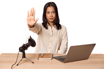 Woman records podcast with laptop standing with outstretched hand showing stop sign, preventing you.