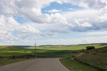 Road in green hills in sunny day. Georgia. Beautiful mountain roadway, grass, blue sky with clouds. Landscape, travel 