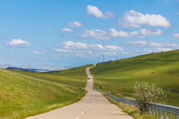 Road in green hills in sunny day. Georgia. Beautiful mountain roadway, green grass, blue sky, white clouds. Landscape