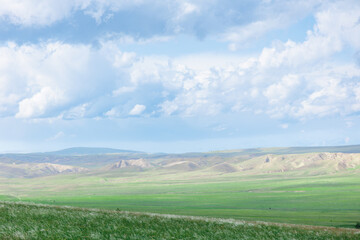 Obraz premium Green field in countryside at sunny day. Beautiful landscape in the mountains. Grassy field and hills. Travel Georgia
