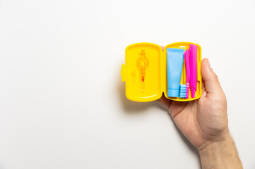 Dental hygiene and oral care products in a yellow travel cosmetic bag on a white background with...