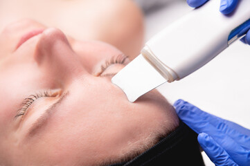 An ordinary, not beautiful European woman receives ultrasonic facial peeling in a spa. Close-up...