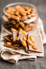 Broken chocolate bar with almonds on kitchen table.