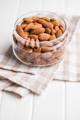 Peeled almond nuts in jar on kitchen table.
