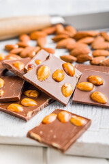 Broken chocolate bar with almonds on kitchen table.