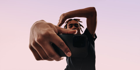 Young man capturing a lifestyle pose with his selfie camera in a studio