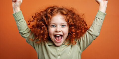 Cute young child Little girl smiles. Emotion and child development. Little girl smiles while red hair. A young girl with curly hair is smiling and laughing while wearing a shirt.