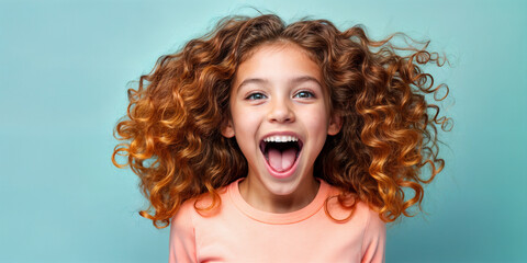 Cute young child Little girl smiles. Emotion and child development. Little girl smiles while red hair. A young girl with curly hair is smiling and laughing while wearing a shirt.