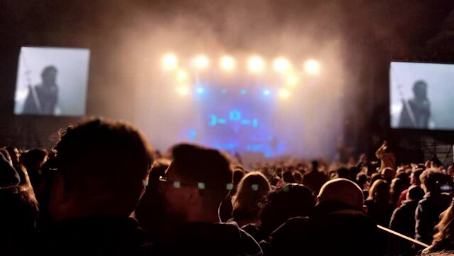 Energetic crowd silhouetted against dazzling stage lights at a nighttime concert
